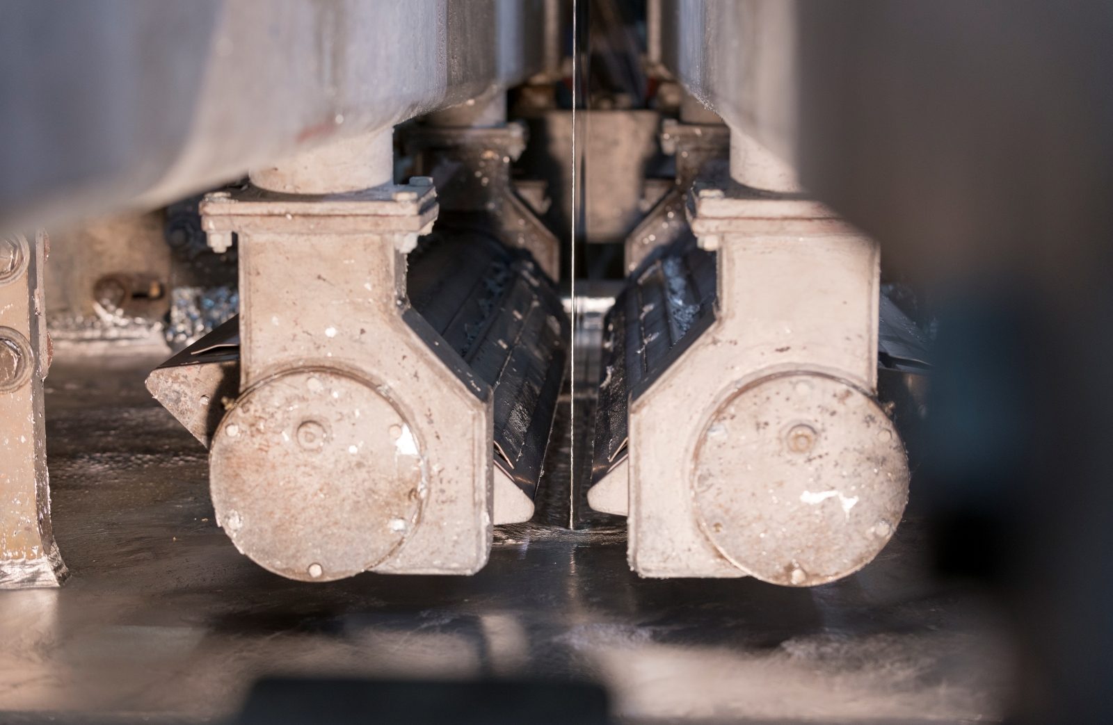 Close-up of steel being processed during the galvanizing or galvannealing stage, showcasing precision industrial equipment.